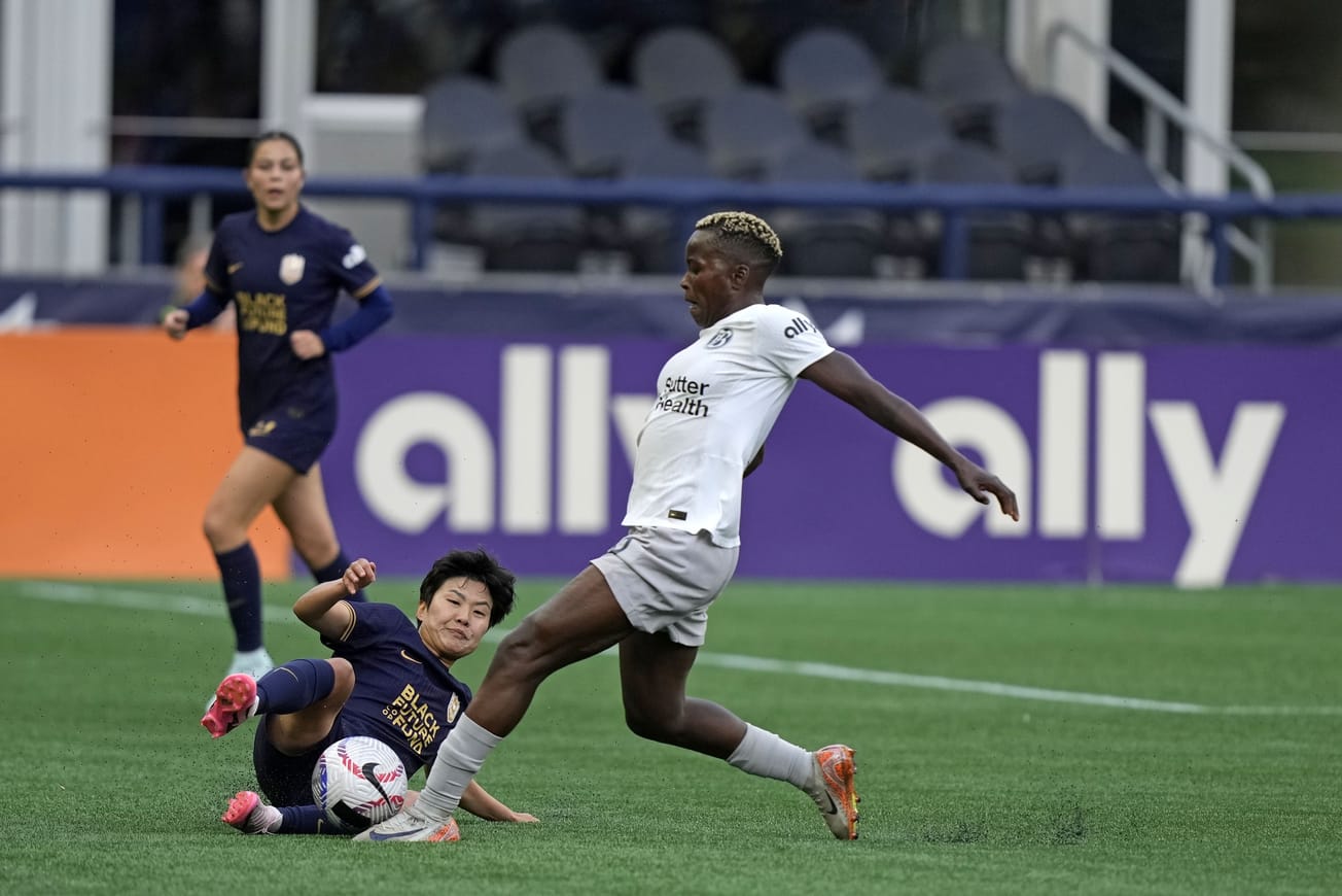 Seattle Reign's Ji So-Yun slides to challenge Bay FC's Racheal Kundanananji for a ball in a September 2024 NWSL match.